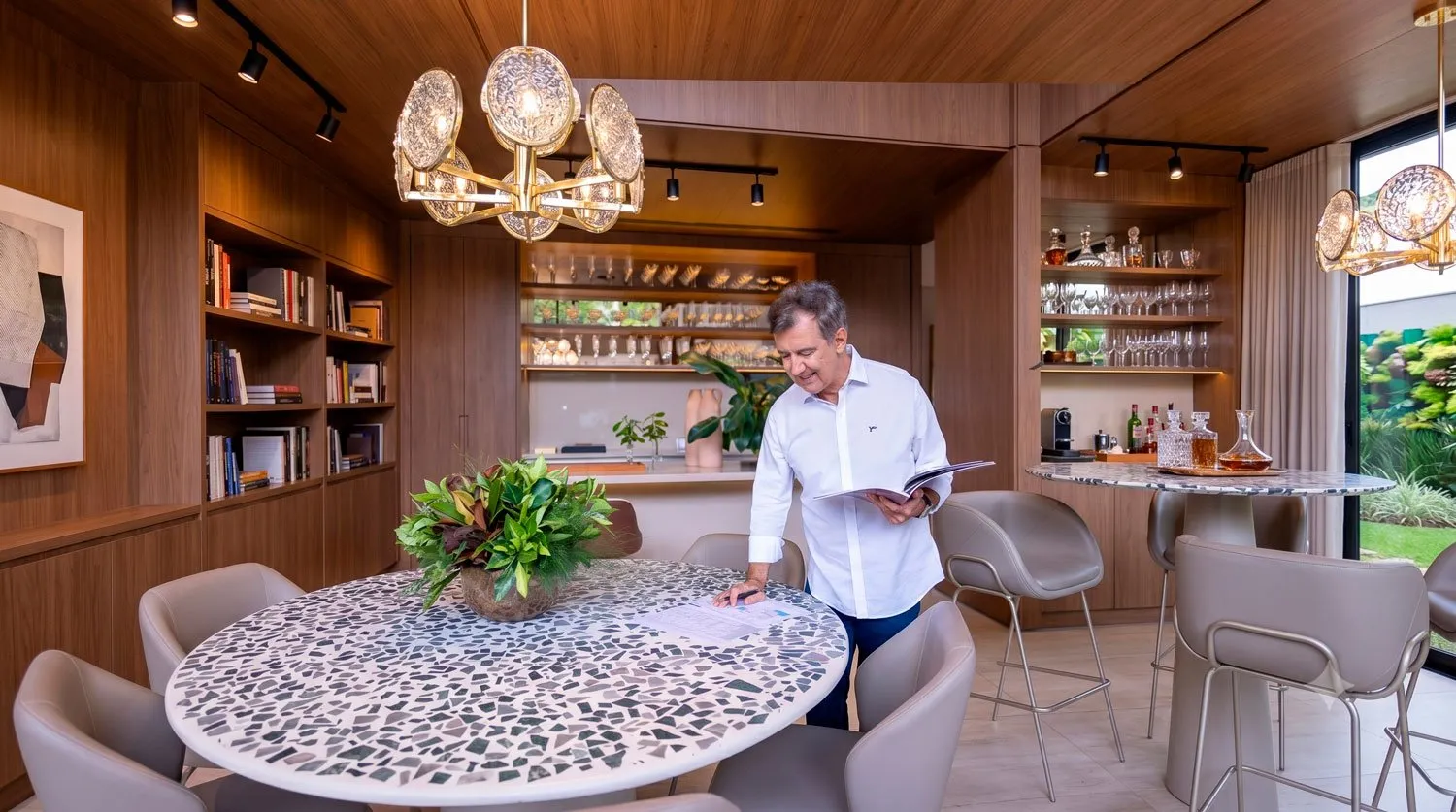 Adalberto Montagnani folheando um projeto em uma cozinha com marcenaria em madeira